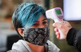 Una mujer entra a un centro comercial con tapabocas.