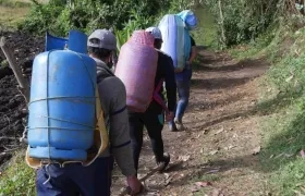 Lorena Erazo, su padre y su hermana cargan con pimpinas de gas, por una trocha entre Tulcán (Ecuador), y la localidad colombiana de Ipiales. 