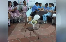 Una foto, dos globos y corales blancos en el pupitre de Samara