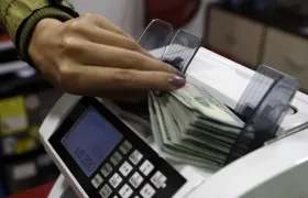Una mujer coloca dólares en una máquina contadora de billetes en una casa de cambio de divisas, en Bogotá.