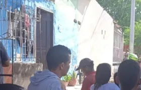 Curiosos se reúnen en el frente de la vivienda en la que fueron asesinadas dos mujeres.