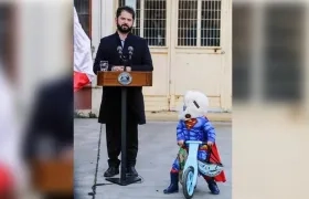 Gabriel Boric en pleno discurso. El niño disfrazado se detiene para observarlo.