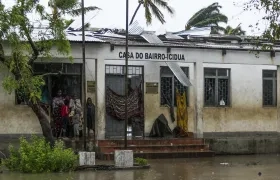 Varias personas se protegen de la lluvia en una calle inundada tras de la destrucción causada por el ciclón Freddy en Quelimane, Mozambique.