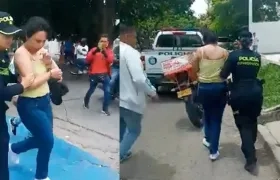 Policías conducen a una mujer luego de robo de un camión de valores cargado de dinero.