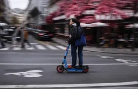 Dos usuarios se movilizan en una patineta eléctrica por las calles de París