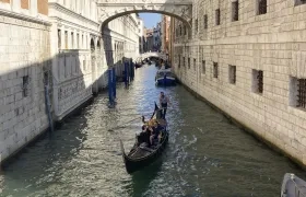 Una pareja disfruta de un viaje en góndola por un canal de Venecia.