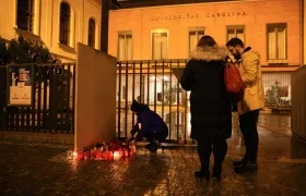 Habitantes de Praga ponen flores ante la fachada de la Universidad Carolina.