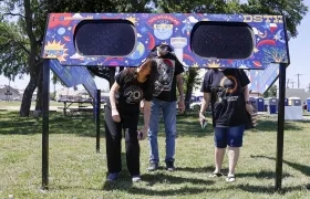 Una familia mira a través de un par de gafas gigantes especiales para el eclipse solar en el Veterans Memorial Park en Dripping Springs, Texas