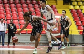 Fabián Jaimes, de Titanes, intenta impedir el avance de Tyrone Perry, de Piratas. 