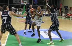 Carlos Morales, de Titanes, apunta hacia la cesta ante la marca de varios rivales.