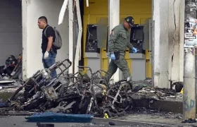Uniformados caminan sobre los destrozos tras el atentado con motocicleta bomba en una estación de Policía en Jamundí