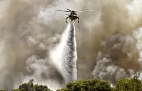 Un helicóptero de extinción de incendios arroja agua durante un incendio forestal. 