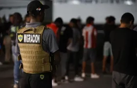 Un agente de migración de Panamá vigila a migrantes antes de ser deportados a Colombia.