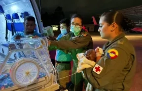 El bebé en manos de personal militar antes de ser ingresado a la aeronave medicalizada.