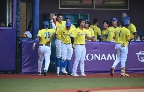 Peloteros de Colombia celebran una carrera en el dugout.