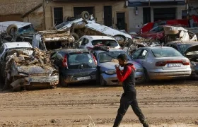 Un hombre camina junto a los coches apilados en Catarroja, Valencia.