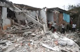 Personas caminan entre los escombros de una casa afectada por una explosión en Mondomo, Cauca.