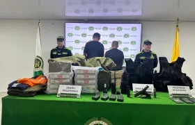 Los dos capturados con las tulas de dinero recuperadas y armas incautadas. 