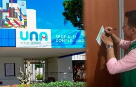 Fachada de la sede de Alta Complejidad y un del funcionario de Supersalud poniendo el sello de intervención.