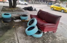 Llantas y un sofá abandonado frente al colegio. 