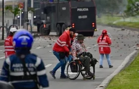 Gestor de convivencia acompañando a una persona en silla de ruedas este viernes, durante protesta en Bogotá.