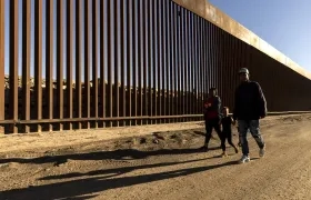 Familia caminando junto al muro fronterizo en Yuma, Arizona.