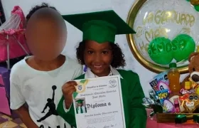 La niña con su diploma de grado y al lado de su hermanito.