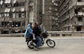 Iraníes pasan en motocicleta frente al hospital Gandhi, destruido en Teherán, Irán.