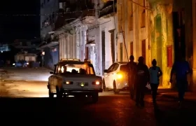 Personas caminan por un sector sin servicio eléctrico en La Habana. 