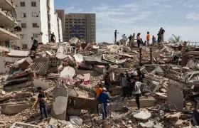 Personas caminan entre escombros de edificios afectado por terremotos