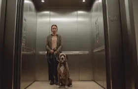 Una mujer con su perro de compañía en un ascensor de un conjunto residencial. 