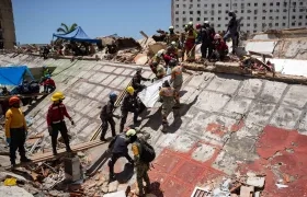 Rescatistas buscan cuerpos entre los escombros.