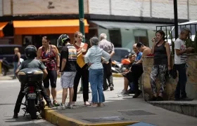 Personas esperan afuera de sus viviendas este viernes. 