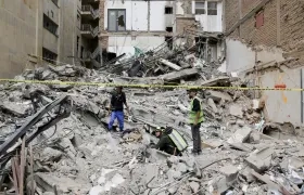 Personas observan los escombros de un edificio afectado por el terremoto en Pereira. 