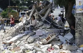 Una mujer espera entre los escombros de un edificio tras el terremoto de magnitud que sacudió a Pereira.