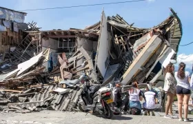 Personas observan una edificación destruida por un terremoto en Manizales