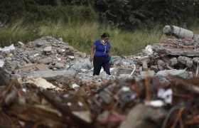 Una persona busca en los escombros de edificios colapsados.