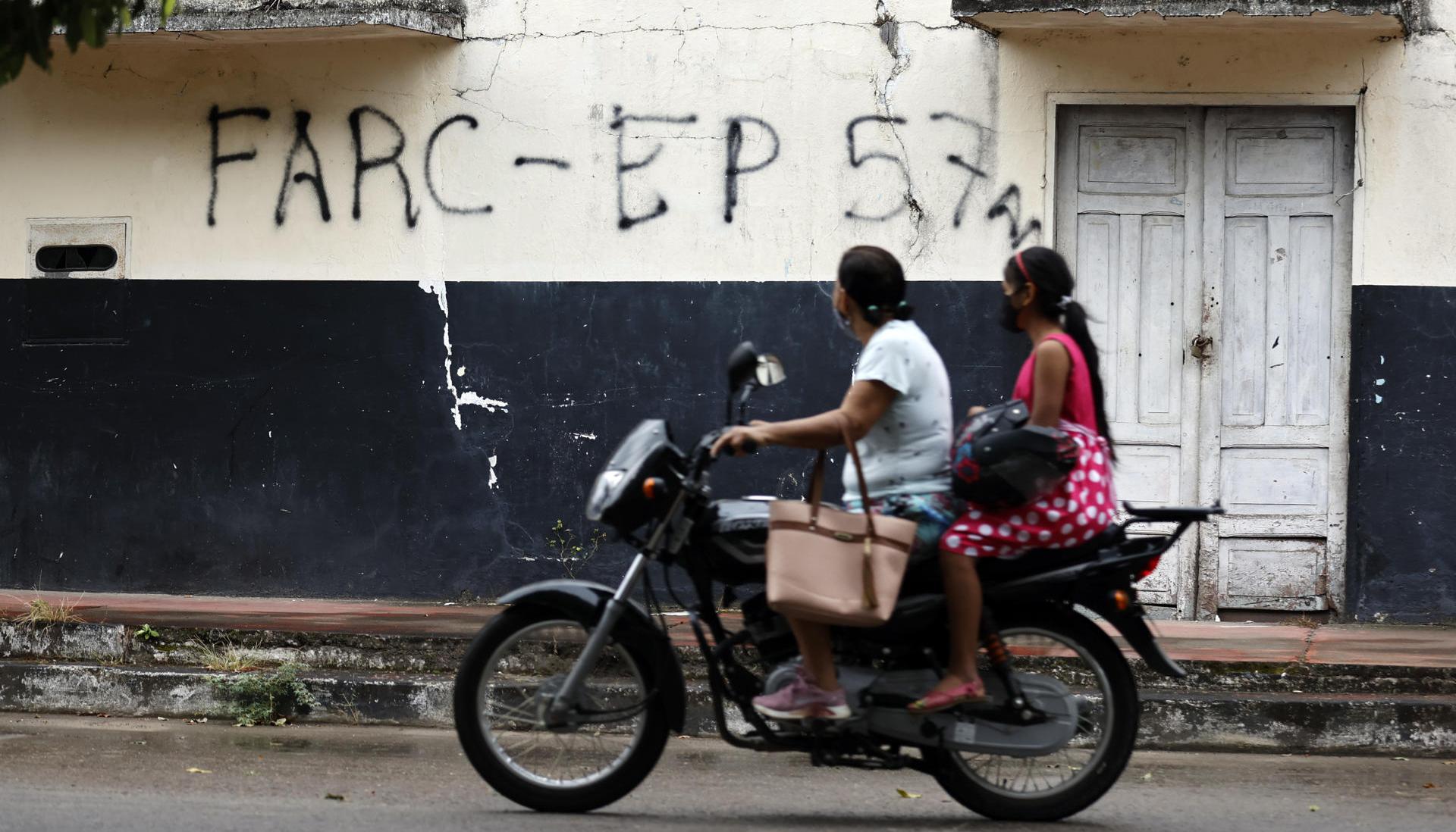 La imagen de archivo muestra a dos ciudadanos de Saravena (Arauca) pasando frente a una pared rayada con las frases FARC y EP.