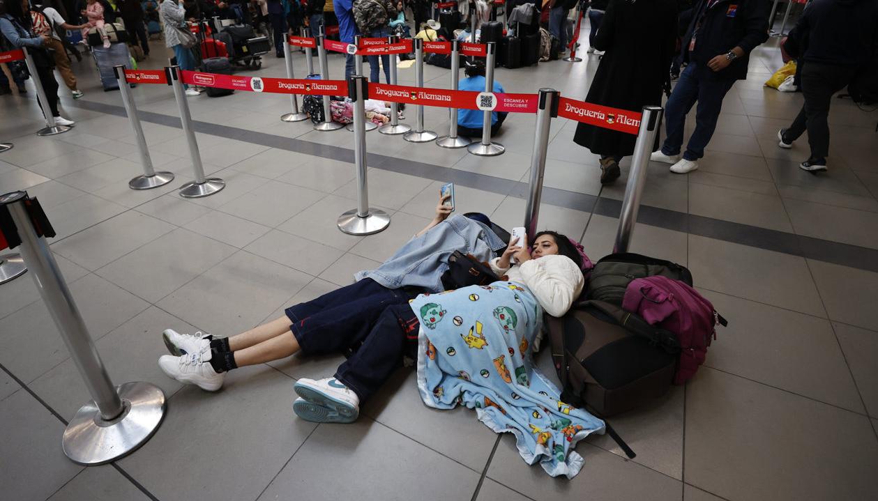 Personas esperan hoy, en el aeropuerto El Dorado de Bogotá.