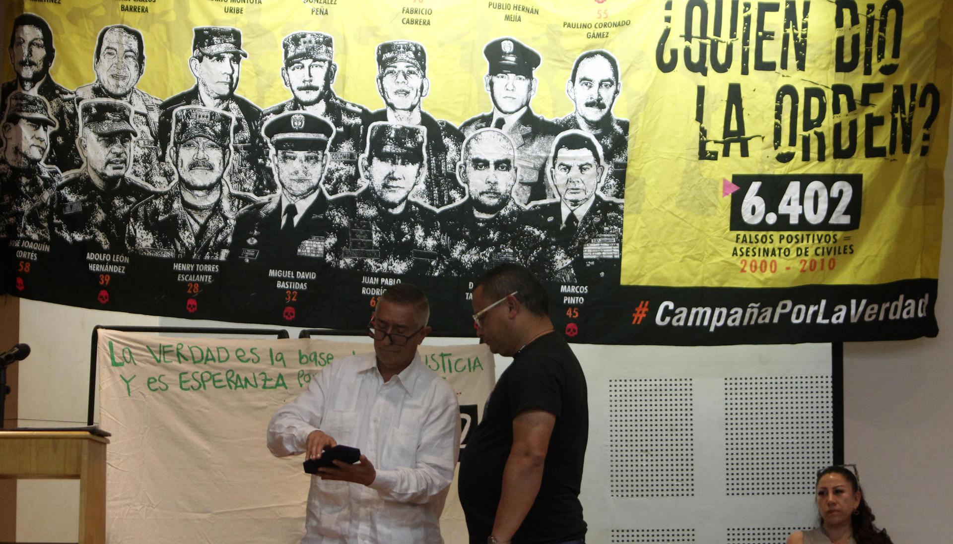  El coronel (r) Jaime Humberto Pinzón entrega una medalla otorgada por sus actuaciones militares hace 18 años a José Alexander Castro, del colectivo Tejiendo Memorias.