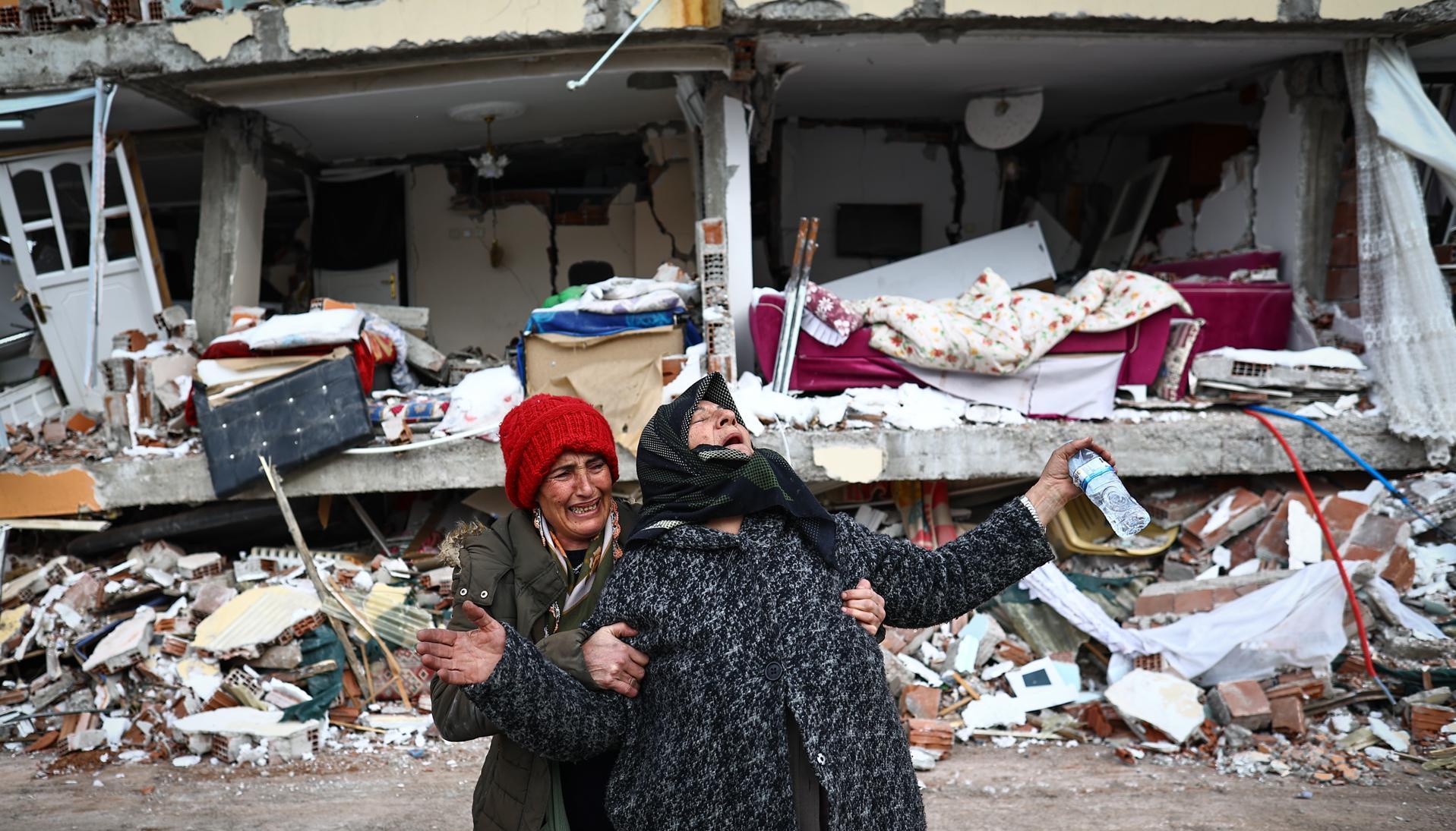 Dos mujeres lloran junto a un edificio derrumbado tras el gran terremoto en el distrito de Elbistan de Kahramanmaras.