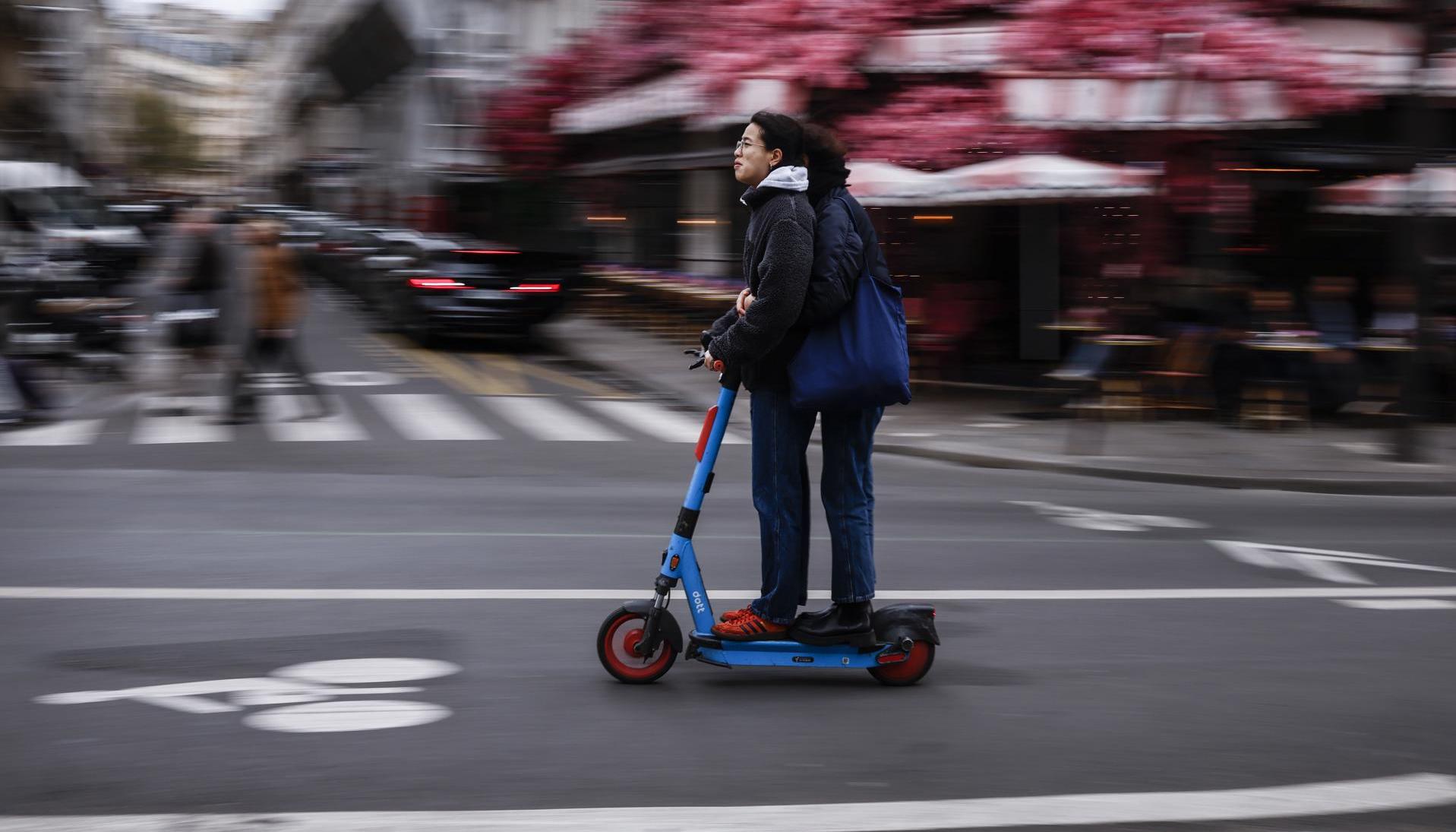 Dos usuarios se movilizan en una patineta eléctrica por las calles de París