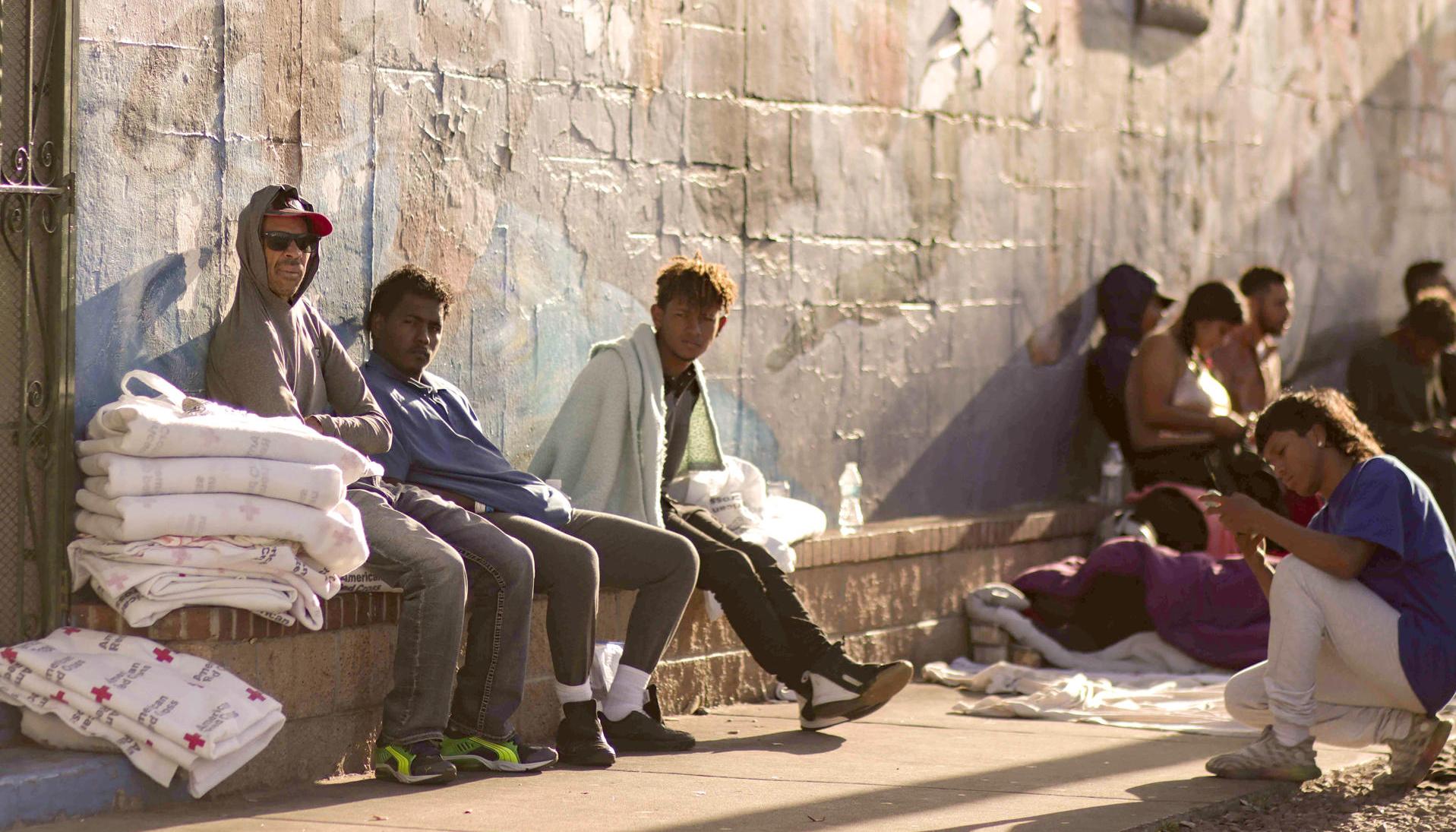 Varios migrantes esperan el sábado en una calle en El Paso, Texas 