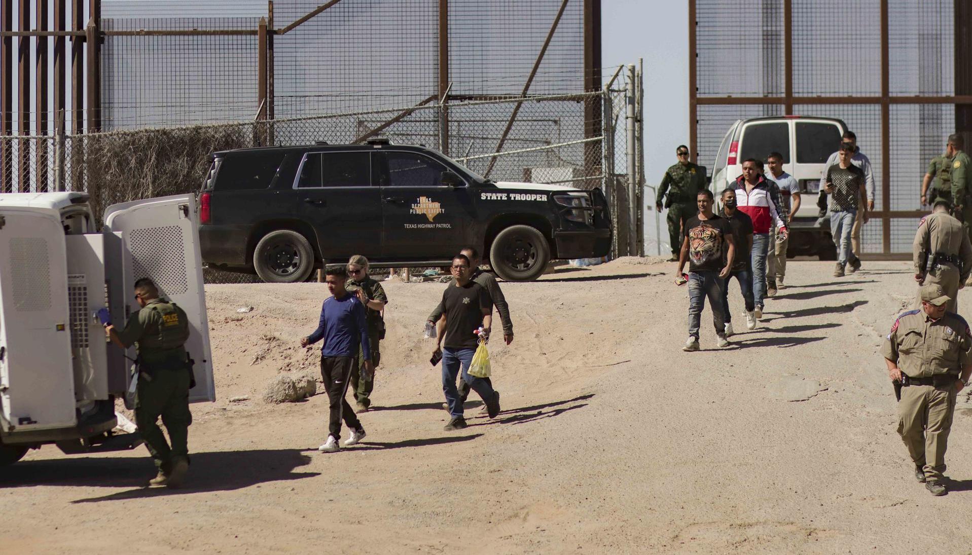 Migrantes detenidos son llevados este jueves por miembros de la Patrulla Fronteriza estadounidense a un vehículo, junto al muro fronterizo en El Paso, Texas 