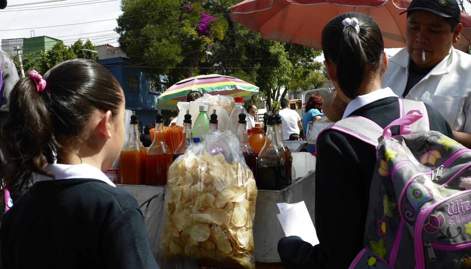 Unas niñas estudiantes compran frituras afuera de un colegio en Ciudad de México