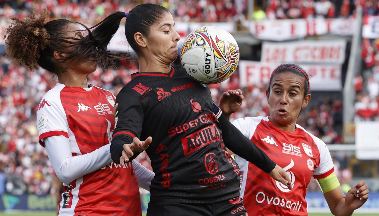 Catalina Usme, capitana del América, protege la pelota ante la marca de dos rivales. 