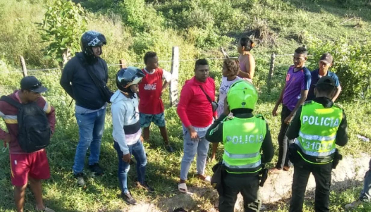 Personas observan el cuerpo del motociclista en el lugar del accidente. 