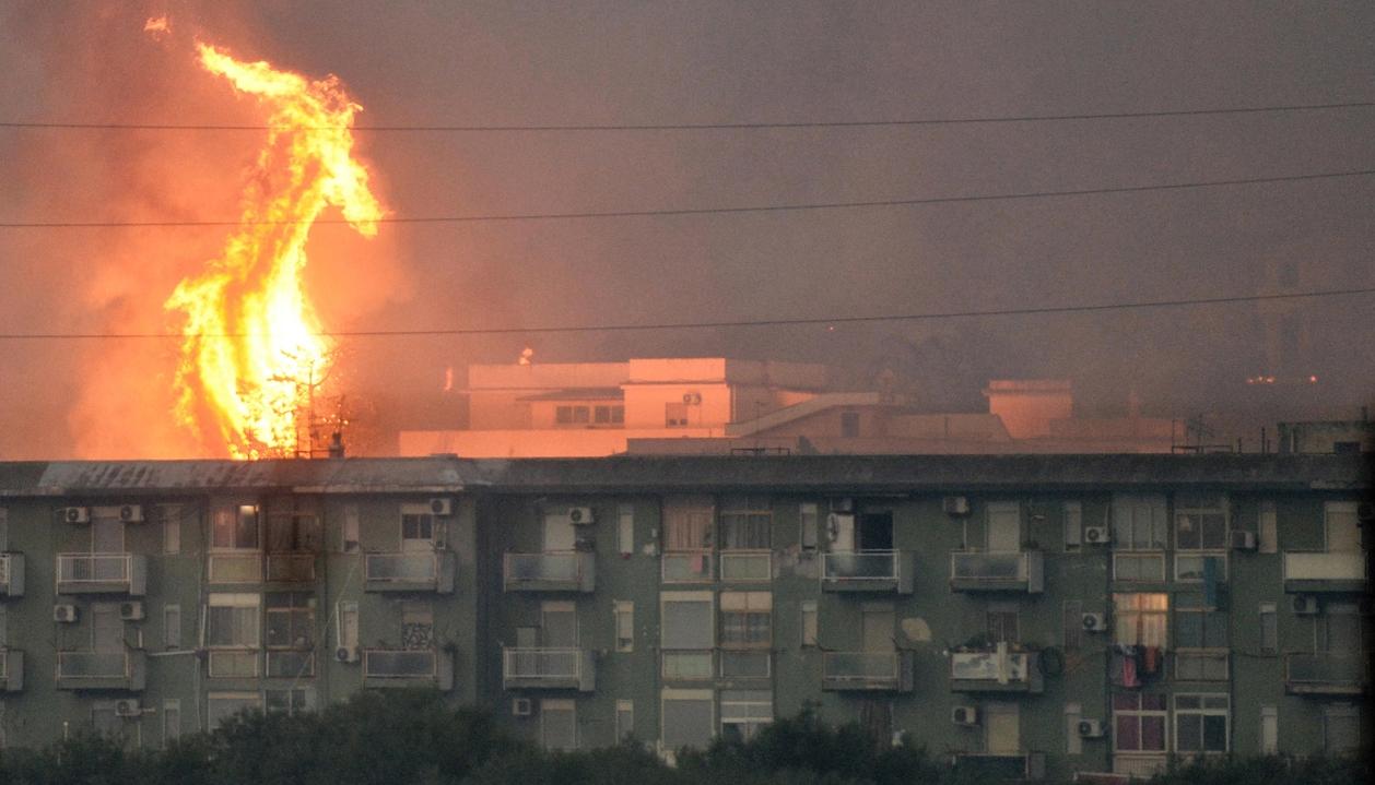 Columna de fuego se eleva tras un bloque de viviendas en el área de Monte Grifone, en Italia.