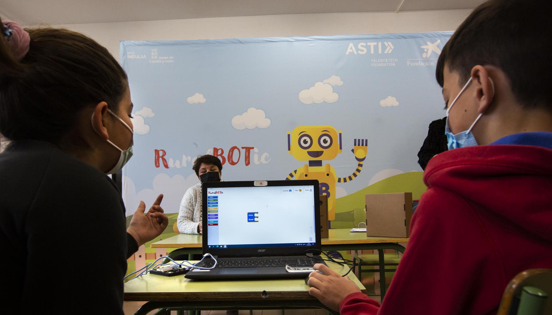 Dos niños manejan un robot por ordenador en un colegio español. 