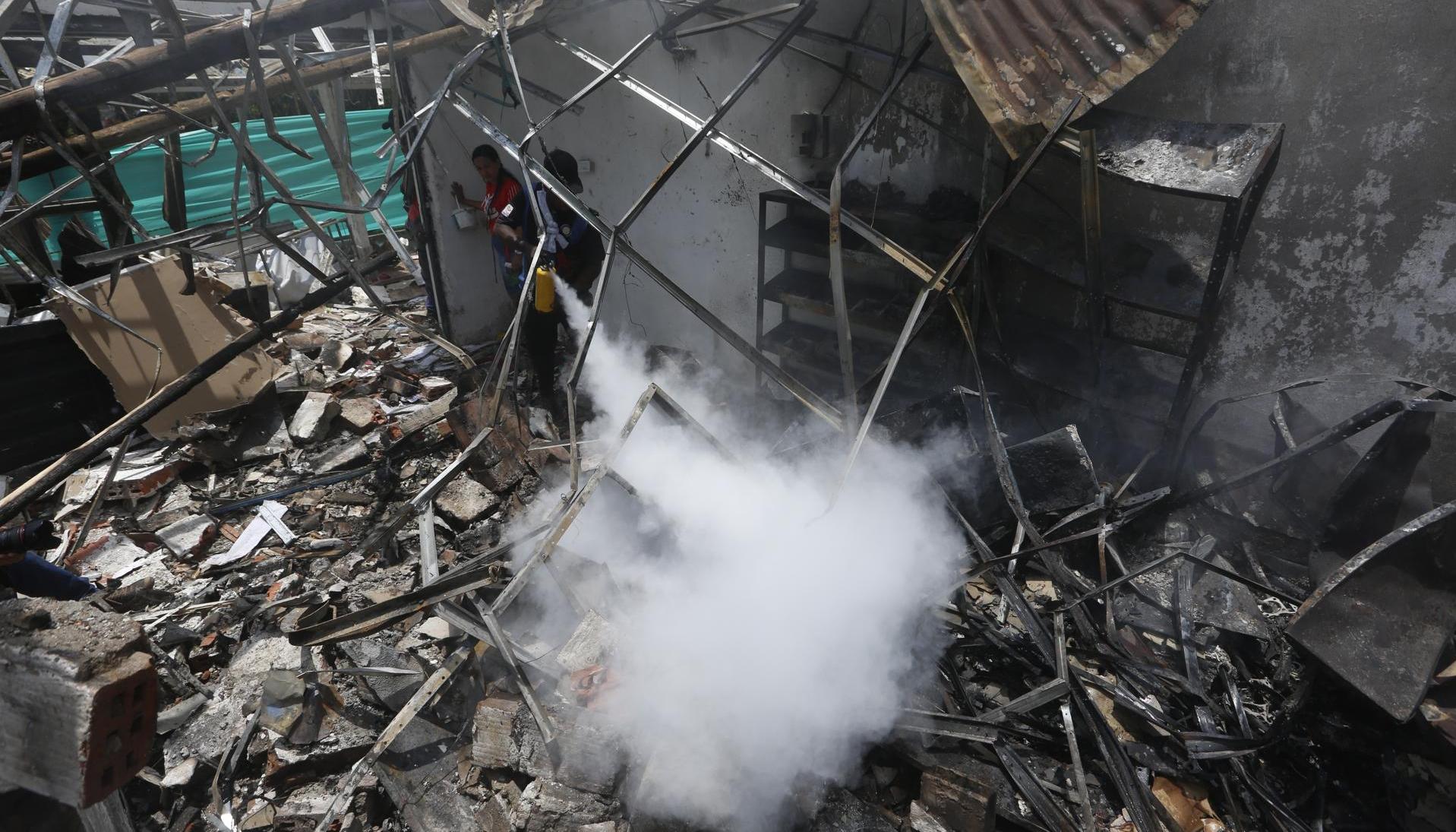 Un hombre usa un extintor en los escombros de una vivienda destruida por un ataque con carro bomba en el Cauca